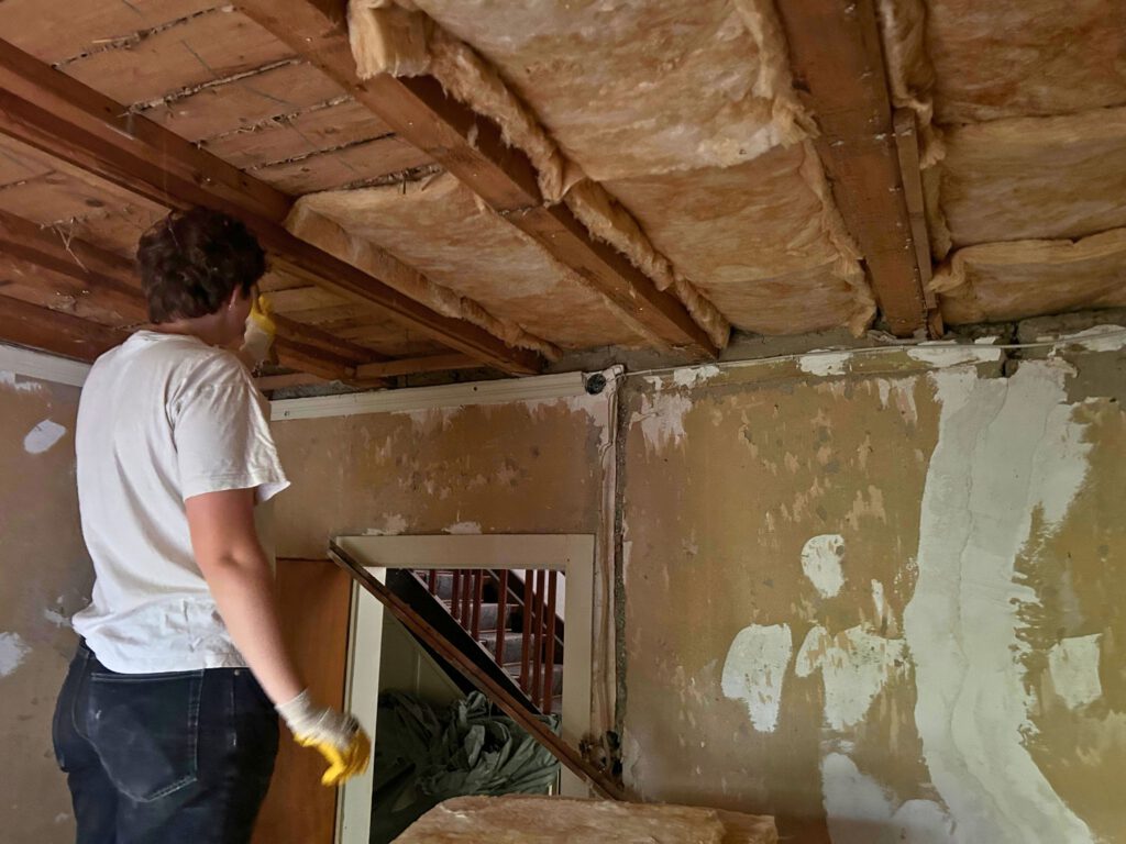 Das Foto zeigt eine Zwischendecke, die von einer Frau gedämmt wird.